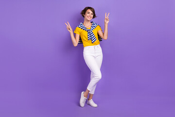 Fototapeta na wymiar Full length photo of lovely glad lady wear yellow outfit arm demonstrate v-sing cool party empty space isolated on purple color background