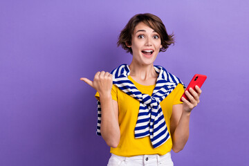 Photo of excited shiny woman wear tied sweater thumb empty space message modern gadget isolated purple color background