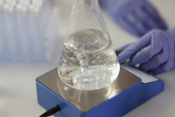 Close-up of flask with boiling liquid on heater in research laboratory.