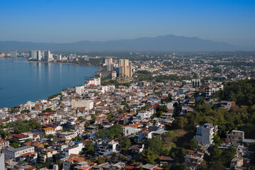 Fototapeta na wymiar Aerial panoramic view of Puerta Vallarta city scape with white houses and clay shingled roofs and Bay of Banderas, sunny day, blue sky.
