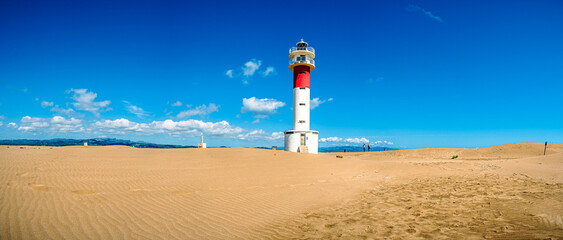 Panorámica de un faro en una playa soleada con cielo azul - obrazy, fototapety, plakaty