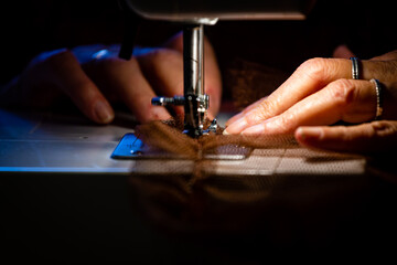 Manos enhebrando el hilo en una máquina de coser