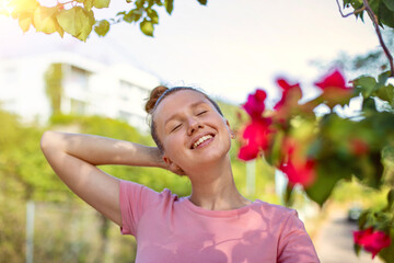 Portrait of happy beautiful girl, young positive woman is smelling beautiful yellow flowers in the...