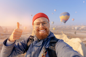 Happy man hipster taking selfie background hot air balloons in Cappadocia. Concept trip Turkey...