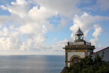 Upper part of the lighthouse of Luarca, Spain, on the sky and the sea in the background