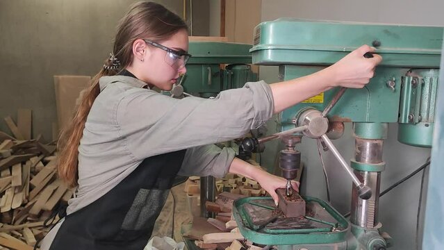 Young woman is training to be a carpenter in workshop.