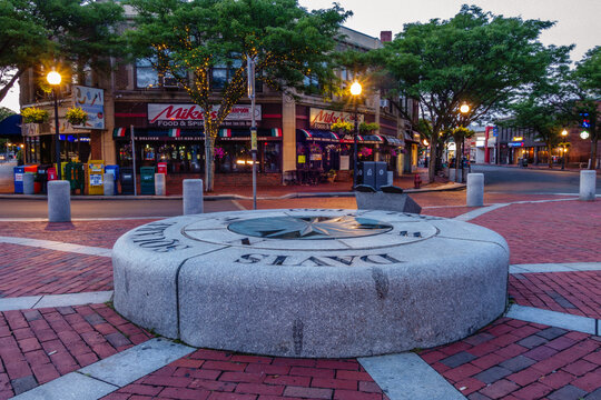 Somerville, MA/USA - August 6, 2017:  View of Davis Square at blue hour with empty streets, light trails and Davis Square sign in foreground and deep blue sky in background.