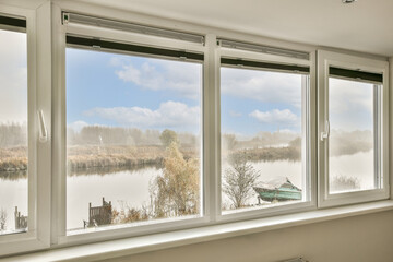 some windows with the view of a lake and trees in the window simh, taken from inside an empty room