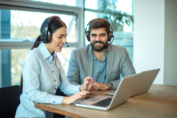 Businesswoman and businessman chatting between each while working together on laptop at office.