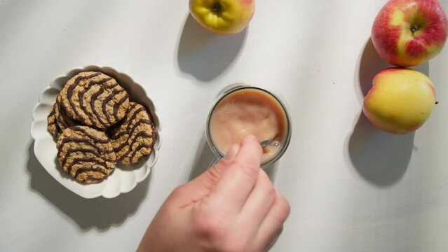 Top View Of Cup With Black Tea And Milk, Stirring Sugar In A Cup With Coffee With Spoon. Cup With Hot Tea And Milk, Man's Hand Stirs Sugar With A Spoon In A Bowl With Coffee Top Down View Slow Motion.