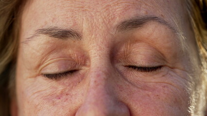 Wrinkled Senior woman closing eyes in meditation and contemplation. Macro close up of an older female person with eyes closed