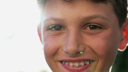 One Happy teen boy smiling at camera standing outside in sunlight. Portrait of a male kid in preteen age years