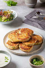 Greek zucchini fritters Kolokithokeftedes on gray background. Zucchini pancakes with feta and herbs, served with greek yogurt.