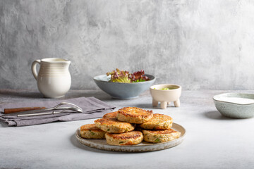 Greek zucchini fritters Kolokithokeftedes on gray background. Zucchini pancakes with feta and herbs, served with greek yogurt.