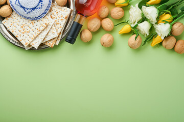 Passover celebration concept. Matzah, kosher red wine, walnut and spring white and yellow rose flowers. Traditional ritual Jewish bread on light green background. Passover food. Pesach Jewish holiday.