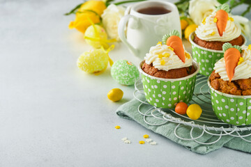 Carrot cake cupcakes for Easter. Carrot cupcakes with cream cheese frosting decorated with tiny marzipan carrots on white background. Happy Easter and spring holiday concept. Holydays homemade dessert