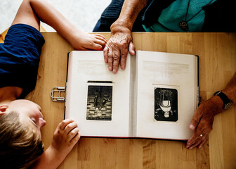 grandparents and grandchild look at an old album with family photos

