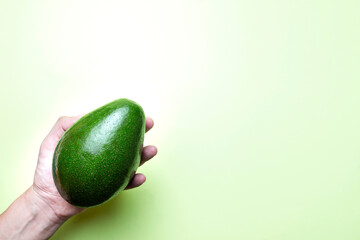 Mão masculina segurando abacate e fundo verde