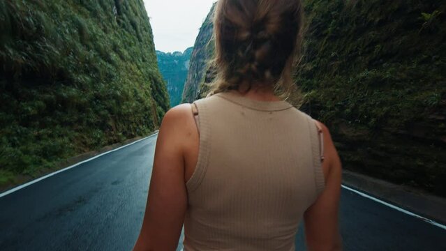 Young woman walks barefoot on the wet asphalt road in the canyon