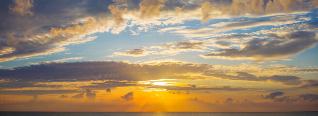 Naklejka na ściany i meble blue cloudy sky and low evenind sun, beautiful dramatic sunset background