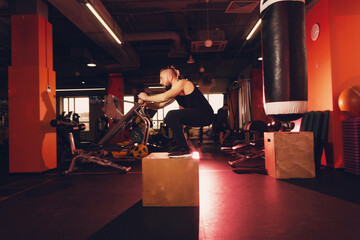 A man with a beard does an exercise jump on a pedestal in the gym.