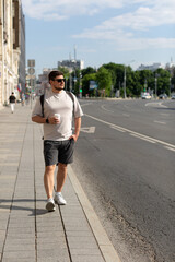 A man walks down a city street with a cup of coffee