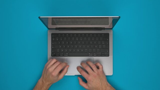 Vue de dessus d'une personne utilisant un ordinateur portable sur un fond bleu uni