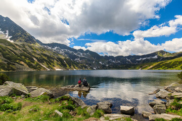 Couple of tourists sitting on a rock in the Valley of five ponds in the Polish Tatras