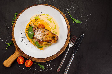 Golden white fish steak with sauce and herbs on wooden background