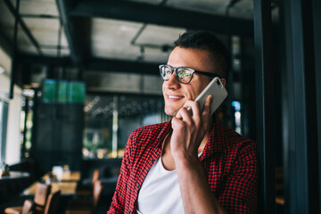 Happy man calling on smartphone in cafe