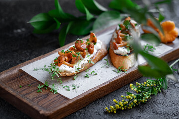 Two Bruschetta with chanterelles and Philadelphia cream cheese on a wooden board. Mushroom sandwich decorated with greens, selective focus