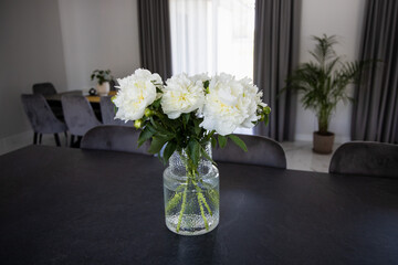 White peony flower bouquet in the crystal vase on the table in modern house