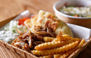 Traditional Greek souvlaki dish served with pita bread and fries on recyclable paper plate
