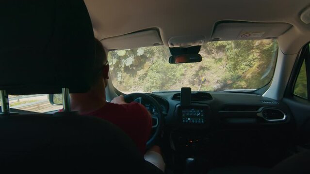 Man steers the car along the narrow road in mountains