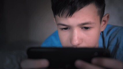 Teenage boy using phone at home in the evening, chatting with friends, playing games indoors, cinematic shot