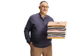 Cheerful mature man holding a pile of folded clothes and smiling at camera