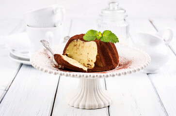 Traditional Italian vanilla pudding with chocolate powder coating served as close-up on a design cake plate