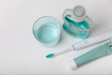 Electronic ultrasonic toothbrush, mouthwash and toothpaste on white textured background. Items for...