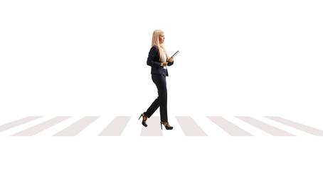 Full length profile shot of a young businesswoman holding documents and walking on a pedestrian crossing