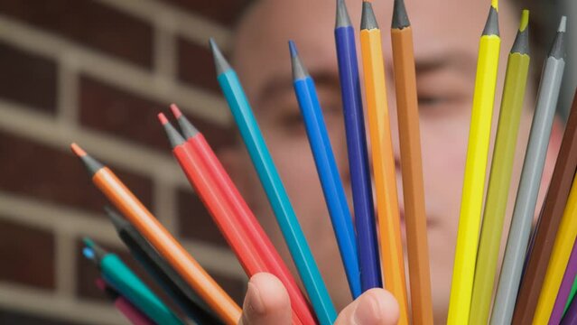 Teenage boy holding colored pencils for drawing, close-up