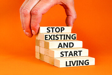 Stop existing start living symbol. Concept words Stop existing and start living on wooden blocks. Beautiful orange table orange background. Business Stop existing start living concept. Copy space.