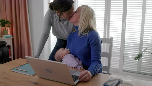 Gay mothers couple and newborn baby working with laptop computer at home - Lgbt family concept