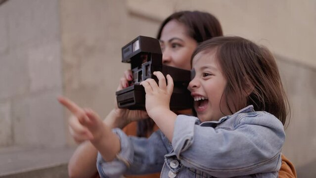 Happy Asian mother and daughter having fun using vintage retro camera outdoor - Family travel