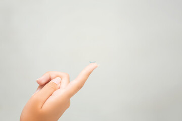 A picture of a young woman trying to put on contact lenses.