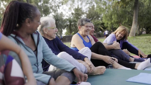 Happy senior people after yoga sport class having fun sitting outdoors in park city - Elderly community