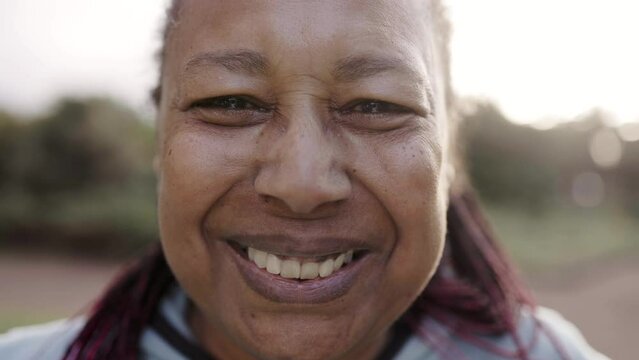 Authentic headshot of happy senior African woman looking at camera outdoor - Real people, diversity and elderly concept