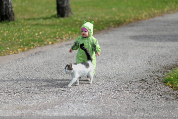 A little girl walks with a cat in the park