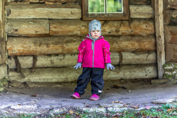 A little girl in front of a historic old log cabin