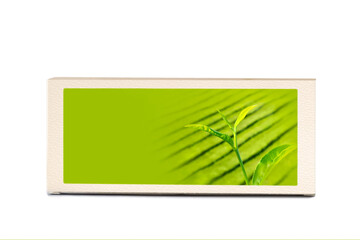 Design template for green tea packaging: blank tea bag box mockup with a photo of young tea leaves at a plantation, isolated on white background.