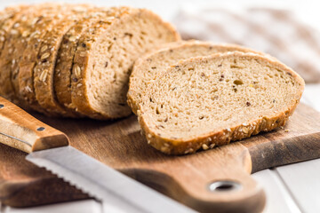 Sliced whole grain bread. Tasty wholegrain pastry with seeds on cutting board.